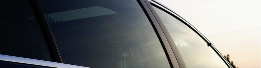 A closeup of a vehicle's tinted windows on the passenger side.